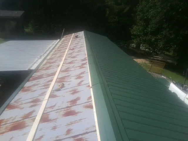 Old rusted panels beside newly installed green metal roofing — Wind Damage Roof Repair by Roofing Brothers in Russellton