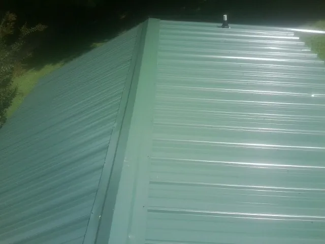 New green metal panels meeting at the ridge of a roof — Flat Roof Repair work by our crew in Russellton