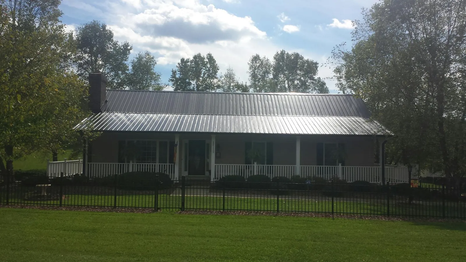 Gray metal roof on a brick ranch with a full width front porch — Gutter Guard Installation work by our crew in Russellton