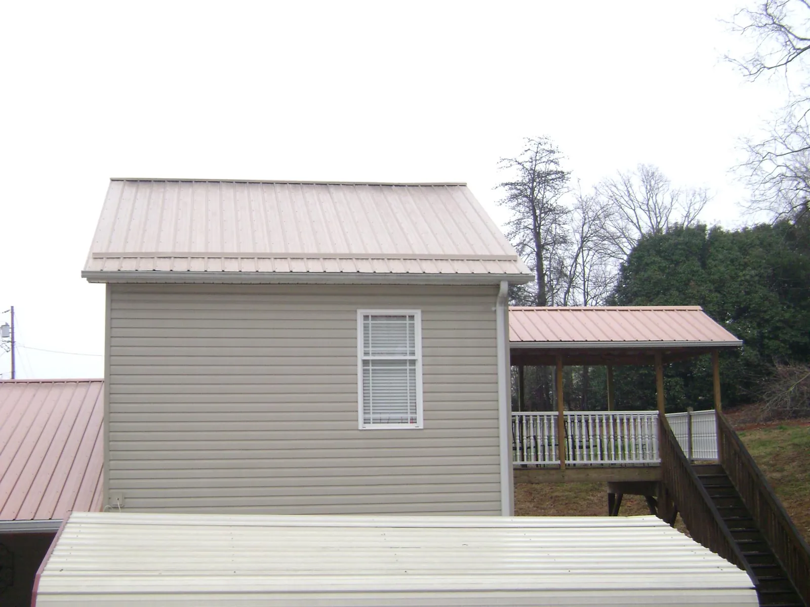 Tan metal roofs on a two story addition and attached porch, from a Roof Replacement job in Russellton