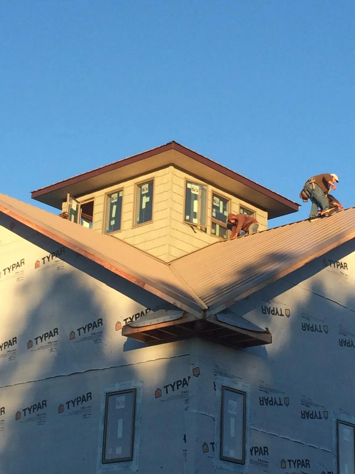 Roofers working around a rooftop cupola on a new metal roof at sunset — Roof Waterproofing in Russellton by Roofing Brothers